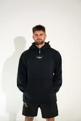 Canguro negro con capucha, cierre frontal parcial y bolsillo tipo canguro. Presenta un estampado gráfico pequeño en el centro del pecho.