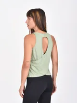 Musculosa deportiva color pistacho con cuello redondo y sisas amplias. Presenta un diseño de capas superpuestas en la espalda y aberturas laterales.