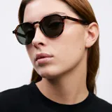 Lentes de sol unisex con armazón geométrico color carey y lentes polarizadas color verde oscuro.