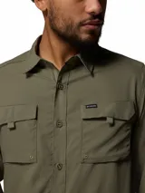 Camisa de manga larga Columbia, color verde militar, con cuello clásico, cierre frontal de botones y dos bolsillos frontales con solapa. Presenta tecnología de protección solar y tejido transpirable de secado rápido.