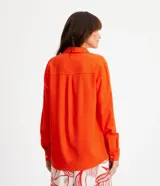 Camisa de manga larga color verde lima, con cuello camisero y botonadura frontal. Presenta un dobladillo trasero más largo que el delantero.