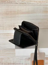 Billetera pequeña de cuero negro con textura de cocodrilo y cierre de cremallera.