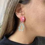 Aros colgantes con base circular rosa, detalle de strass y dije transparente con diseño abstracto celeste.