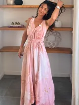 Vestido largo sin mangas con escote en V pronunciado, de corte amplio y fluido, con estampado abstracto en tonos rosados, marrones y blancos, y un cordón trenzado ajustable en la cintura.