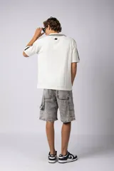 Remera tipo chomba tejida de algodón color negro, con cuello en V y mangas cortas. Presenta detalles de rayas blancas en cuello y mangas, y estampados con logos en el frente.