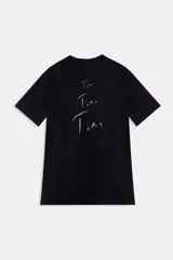 Remera negra de algodón con cuello redondo y mangas cortas, perteneciente a la colaboración Tini x Under Armour. Presenta un estampado gráfico frontal de estilo Y2K con la inscripción 'FUTTTURA' y la imagen de la artista Tini, además de una etiqueta deportiva en el dobladillo inferior derecho.