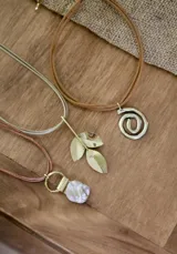 Collar con cadena doble color beige y dije colgante dorado con forma de tres hojas.