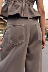 Jeans de tiro medio con corte wide leg y pernera ancha. Presenta pinzas delanteras, bolsillos frontales, bolsillos de plastrón en la espalda y cierre frontal con cremallera, botón interior y ganchos metálicos.