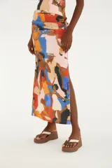 Falda larga fluida de tiro alto, confeccionada con tejido elástico y estampado multicolor de estilo artístico con figuras humanas. Cuenta con una abertura lateral en el bajo.