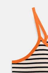 Top corto de punto con diseño de rayas horizontales blancas y negras. Presenta ribetes en color naranja vibrante en el escote y los tirantes finos.
