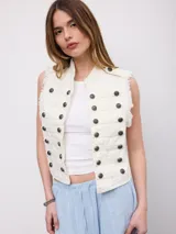 Chaleco vaquero blanco de estilo militar, con doble botonadura frontal de botones oscuros y diseño sin mangas con bordes deshilachados.