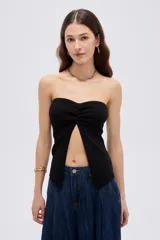 Top de viscosa negro, sin mangas, con escote strapless y frunce central en el escote que genera una abertura frontal.
