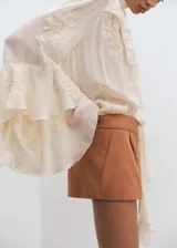 Short tipo falda pantalón de tiro bajo, color tostado, con diseño de tablas y bolsillos laterales.