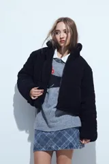 Campera puffer de corderito negro con cuello alto y diseño oversized. Presenta una textura tipo teddy, cierre frontal y corte a la cintura.