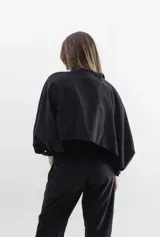 Camisa de seda peletizada con diseño de sobrecapa integrada, cuello mao, mangas abullonadas y cierre frontal con botones al tono.