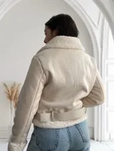 Chaqueta color crema con cuello y puños de piel sintética, cierre frontal con cremallera y cinturón ajustable en la cintura.