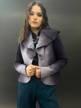 Chaqueta corta de lana merino afieltrada, color gris degradado, con mangas largas y cuello amplio que puede anudarse al frente.