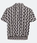 Blusa de viscosa con estampado geométrico en blanco y negro, escote de pico, manga corta y bajo elástico.