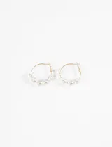 Aros tipo argolla dorados con cuentas de acrílico transparentes con efecto iridiscente.