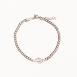 Pulsera de cadena plateada con un dije ovalado central adornado con cristales pequeños y un cristal más grande en el centro. Cuenta con cierre de mosquetón y cadena de extensión.