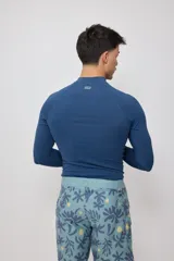 Remera técnica de natación manga larga con protección UV, color azul, con cuello alto y logo de la marca estampado en el pecho.