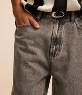Bermuda baggy de jean color negro con pespuntes contrastantes, cierre de botón y cremallera, y bolsillos.