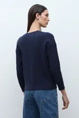 Cardigan bordó de manga larga con cuello redondo y cierre frontal de botones. Presenta un tejido con patrón de estructuras.