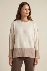 Sweater oversize de lana con diseño color block, combinando un cuerpo en tono crema con motas multicolores y una franja inferior ancha en color visón. Presenta cuello redondo y detalles acanalados en el cuello, puños y ruedo, además de franjas laterales texturizadas en las mangas.