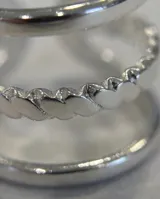 Set de tres anillos de acero quirúrgico plateado, con diseños minimalistas que combinan una banda lisa, una trenzada y otra con detalles geométricos.