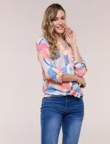 Blusa estampada Zac & Rachel con diseño floral en tonos rosados, azules y amarillos sobre base blanca. Presenta escote en V con botones frontales, mangas tres cuartos con presilla para arremangar y detalle de nudo en el ruedo.