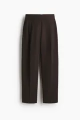 Pantalón de corte holgado en sarga color marrón oscuro. Modelo de tiro alto con trabilla ajustable de botón a ambos lados de la pretina, cierre con corchete oculto, piernas barrel con pinzas, pliegues adelante y atrás, bolsillos al bies y bolsillos traseros decorativos.