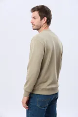 Buzo deportivo color caqui con cuello redondo, mangas largas y puños y dobladillo acanalados. Cuenta con interior en micropolar y un pequeño logo bordado al tono en el pecho.