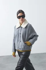Campera corta de paño color gris con cuello de corderito blanco, cierre frontal con botones y bolsillos laterales.