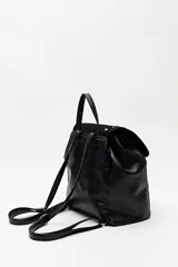 Mochila negra de símil cuero texturizado con tapa en acabado gamuzado, decorada con apliques de tachas metálicas. Tiene asa superior y correas regulables.