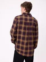 Camisa de manga larga confeccionada en franela de algodón, con diseño de cuadros en tonos verde y marrón. Presenta cuello clásico, cierre frontal con botones y dos bolsillos en el pecho con solapa.