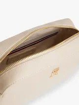 Cartera bandolera de poliuretano color beige, de diseño estructurado con compartimento principal con cierre, bolsillo interior y correa ajustable. Cuenta con el logo metalizado de la marca en el frente y detalles dorados.
