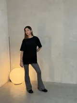 Pantalón tipo calza de tiro alto con corte acampanado, confeccionado en lycra con estampado de lunares blancos sobre fondo negro.