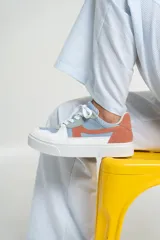 Zapatillas bajas de cuero color blanco con detalles en celeste, verde y naranja.