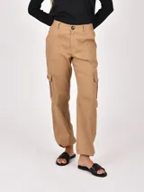 Pantalón cargo color tostado, de corte recto y tiro medio, con bolsillos laterales tipo cargo y bolsillos frontales. Cuenta con cierre de botón y bragueta.