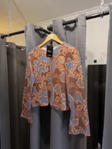Sweater de corte cropped con diseño estampado estilo paisley en tonos marrones y celestes, cuello redondo y mangas largas.