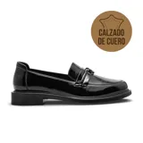 Zapato tipo mocasín de cuero negro con acabado charolado, diseño clásico con detalle de tira sobre el empeine y suela plana de goma.