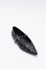 Zapato bajo tipo bailarina de color marrón oscuro, con puntera afilada y tira con hebilla sobre el empeine. El cuerpo del zapato está adornado con múltiples ojales metálicos plateados.