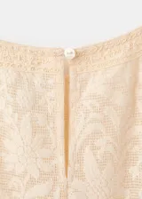 Camisa de diseño recto en tono beige, confeccionada con tejido combinado y panel de encaje frontal. Presenta cuello redondo, mangas largas abullonadas con puños elásticos y detalle de volantes en la cintura.