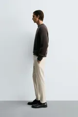 Pantalón de corte slim fit confeccionado en tejido elástico, con cintura elástica, cierre frontal con cremallera y botón, bolsillos laterales y bolsillos traseros de vivo.