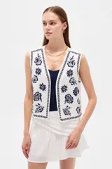Chaleco sin mangas de algodón color blanco, con escote en V y bordados florales en azul marino.