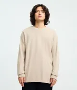 Remera de manga larga con cuello redondo, confeccionada en algodón. Presenta un corte comfort holgado y una pequeña etiqueta decorativa en el bajo.