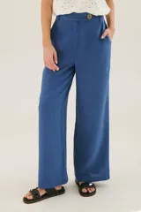 Pantalón de lino azul de corte recto y amplio, con cintura elastizada, cierre de cremallera y botón. Presenta detalles de pespunte blanco en los bordes de los bolsillos.