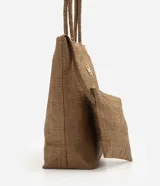 Cartera amplia confeccionada en fibra de papel, de color beige, con asas de hombro, cierre superior y detalle metálico dorado claro en el frente.