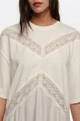 Vestido largo color crudo de manga corta, con inserciones de encaje transparente en forma de V en el pecho y detalles de encaje en el dobladillo inferior.