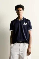 Polo de corte relajado confeccionado en tejido técnico, con diseño de rayas verticales en tonos azul marino y negro. Presenta cuello solapa con abertura frontal y detalles de rib en contraste en cuello y mangas. Incluye estampado frontal con el número 98 y la inscripción France, además de una etiqueta aplicada en el ruedo inferior.